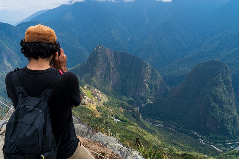 Turista fotografiando Machu Picchu desde la Montaña