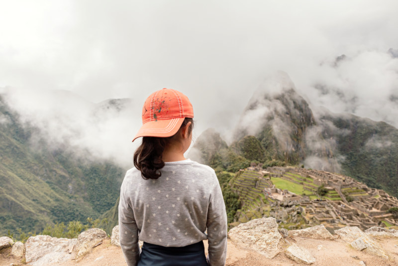 Niña contemplando  el sitio arqueológico de Machu Picchu