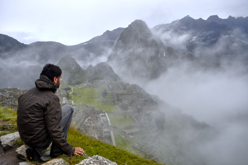 Turista observando a cidadela inca em um dia nublado