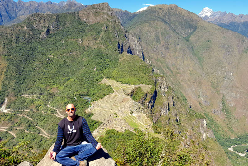 Turista meditando no cume da montanha Huayna Picchu