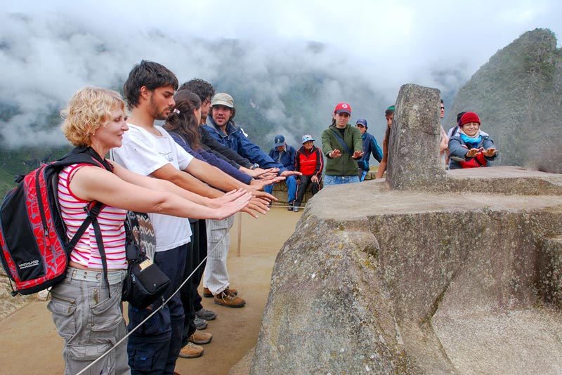 Tourists feeling the energy of Intihuatana – Machu Picchu