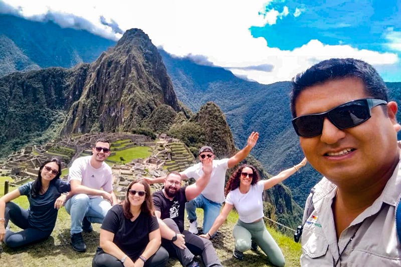 Guide taking photo with group of tourists in Machu Picchu