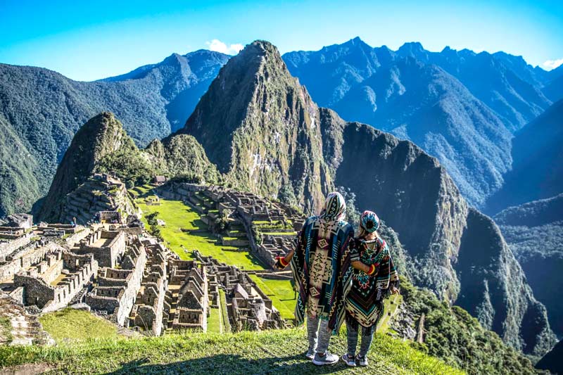 Couple of tourists looking at the buildings of Machu Picchu